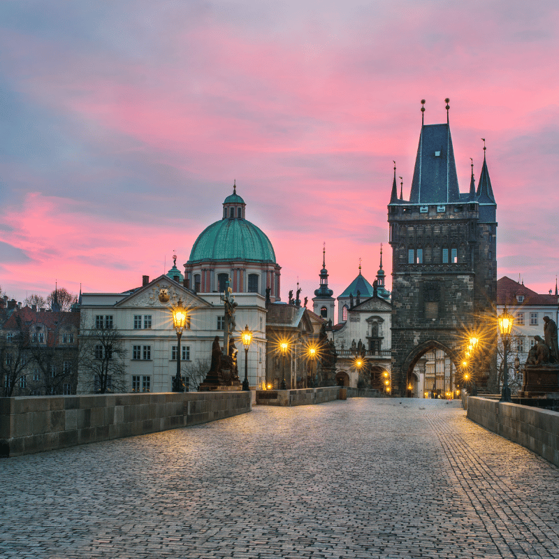 Panoramic view of Prague, Czech Republic, showing the Vltava River, Charles Bridge, and Prague Castle rising above the historic city skyline under a clear sky.