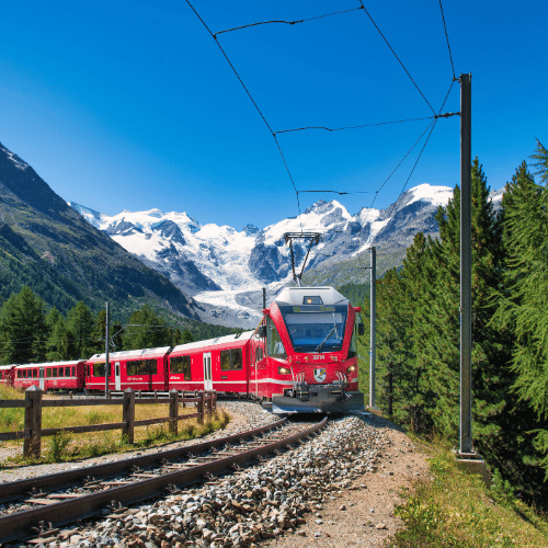 Red panoramic train travelling along the Bernina railway in Switzerland, crossing a stone viaduct surrounded by alpine mountains and dramatic scenery.
